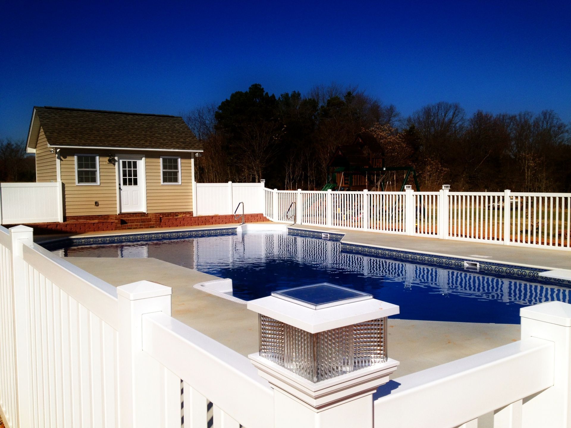 A large swimming pool with a white fence around it