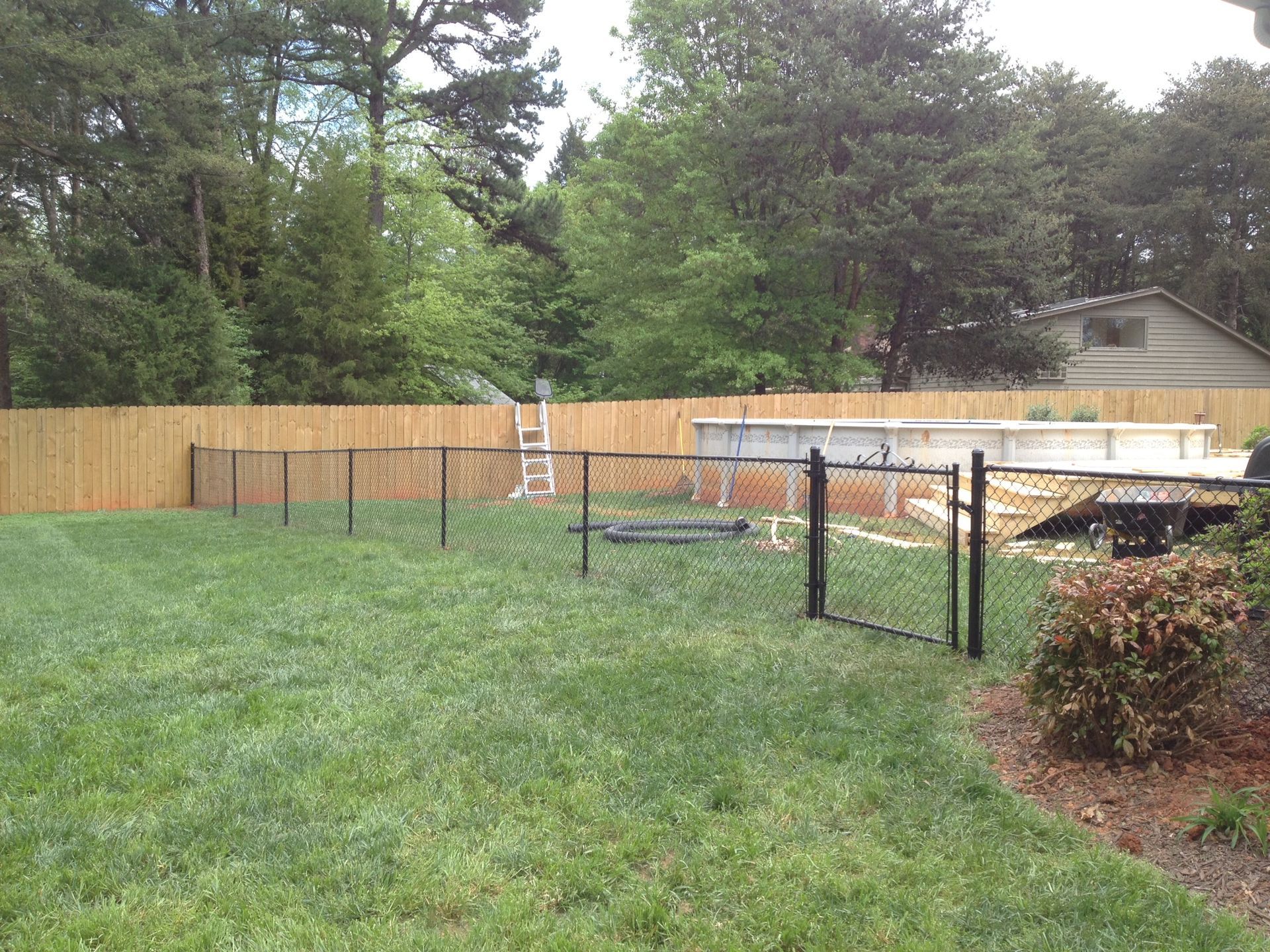 A backyard with a wooden fence and a metal gate