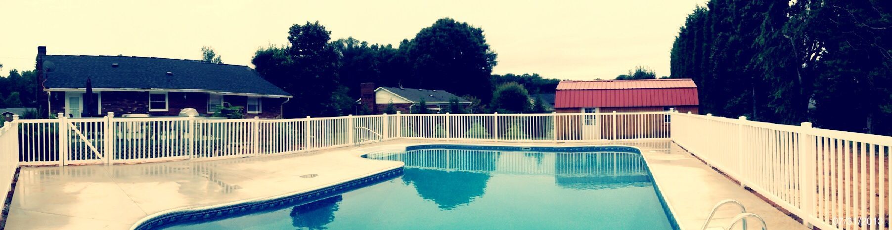 A large swimming pool with a white fence around it