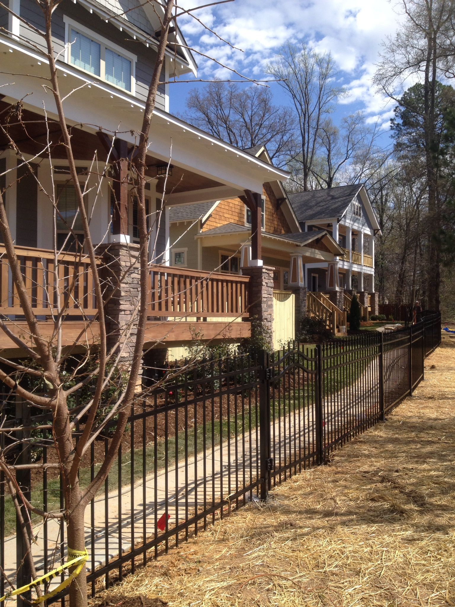 A black fence surrounds a house with a wooden deck.