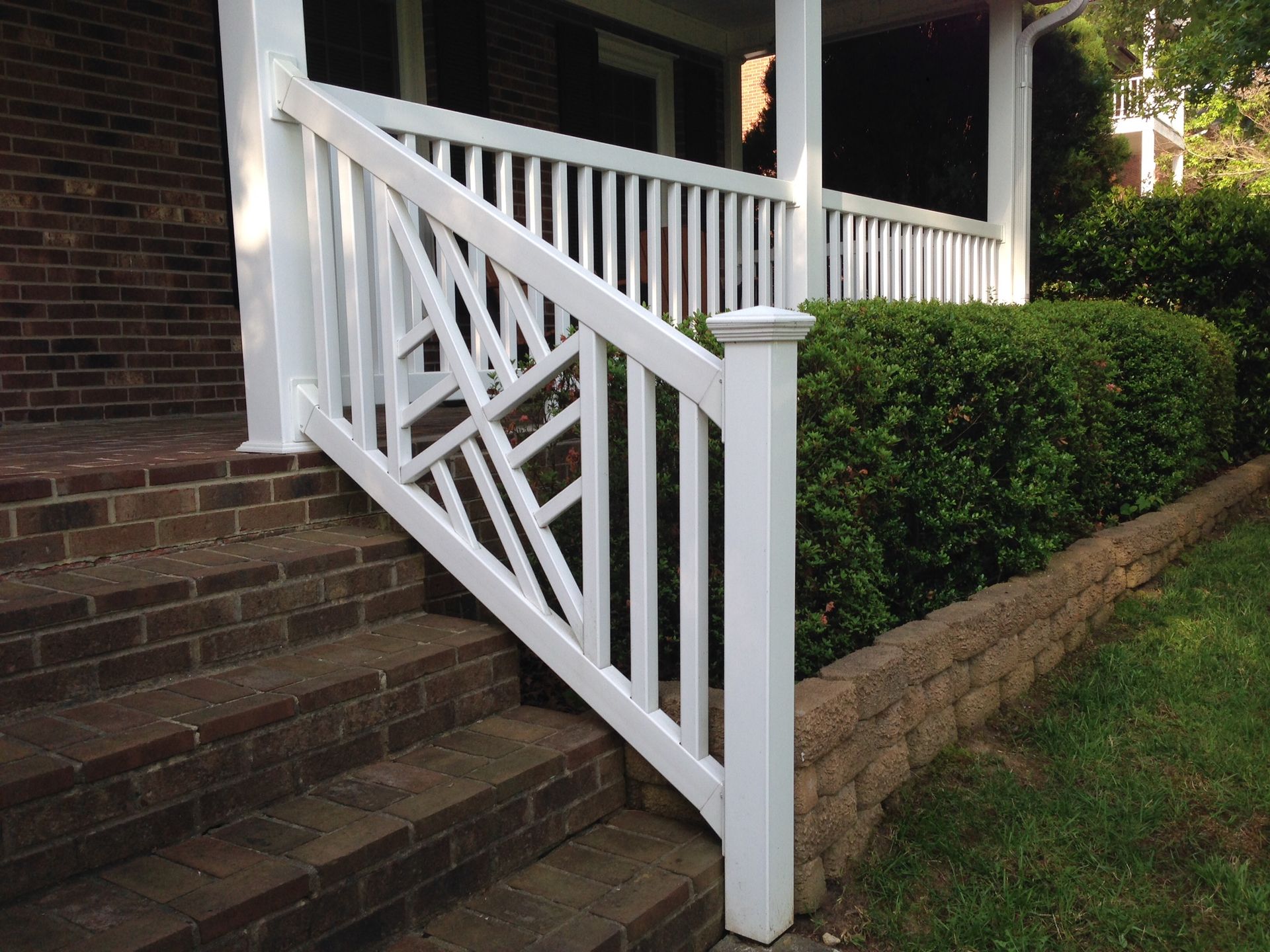 A white railing on a porch of a brick house