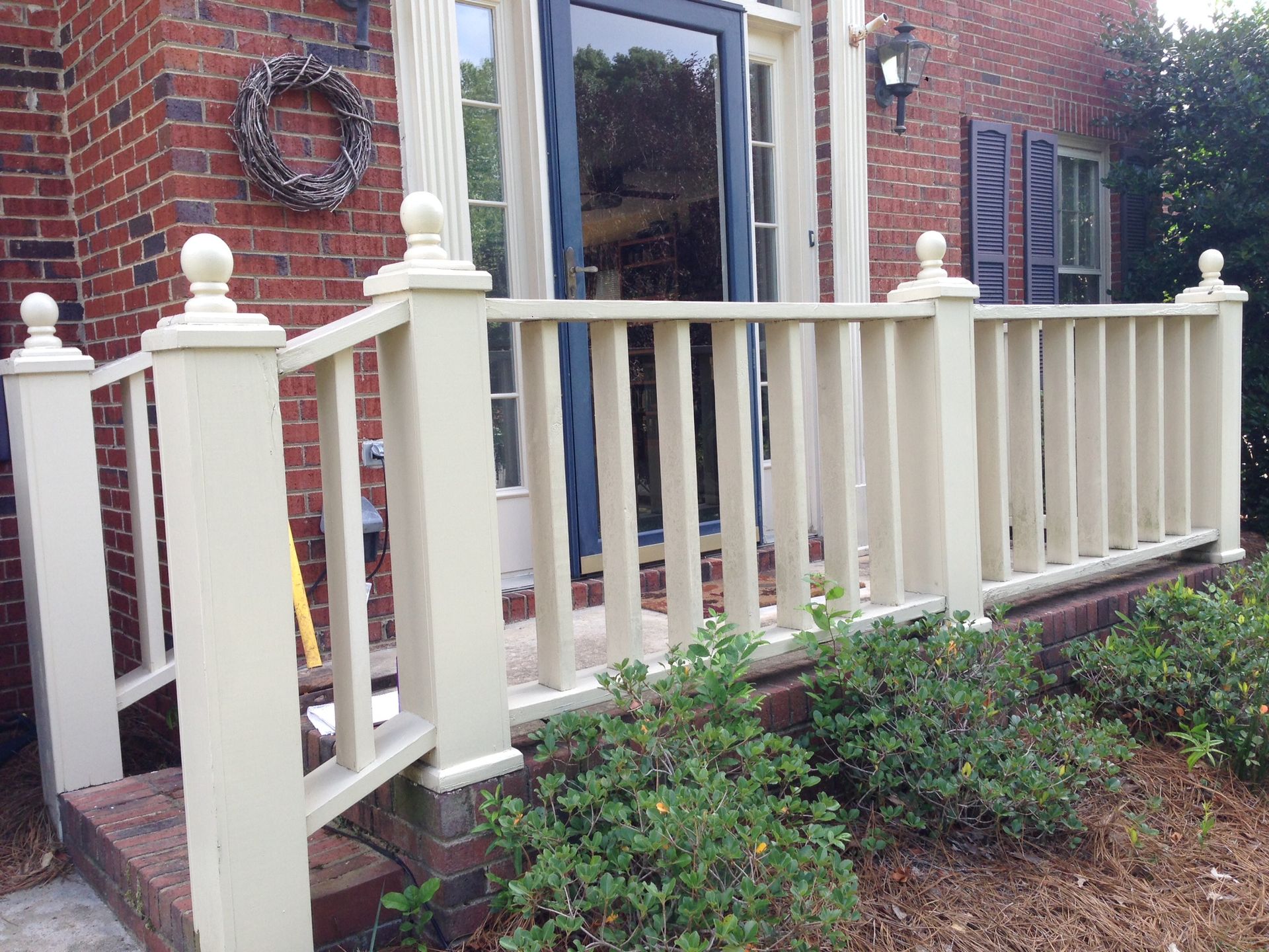 A white railing is in front of a brick house