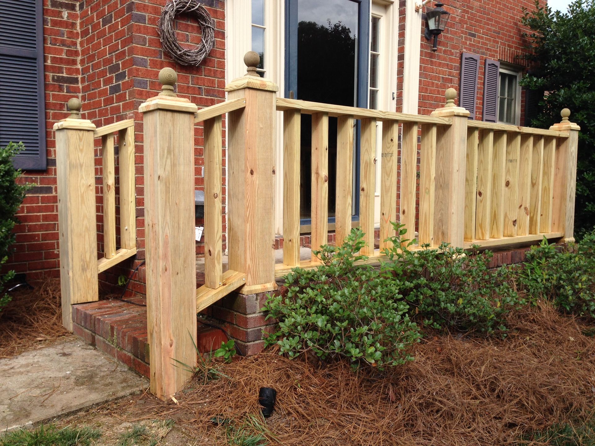 A wooden railing is in front of a brick house