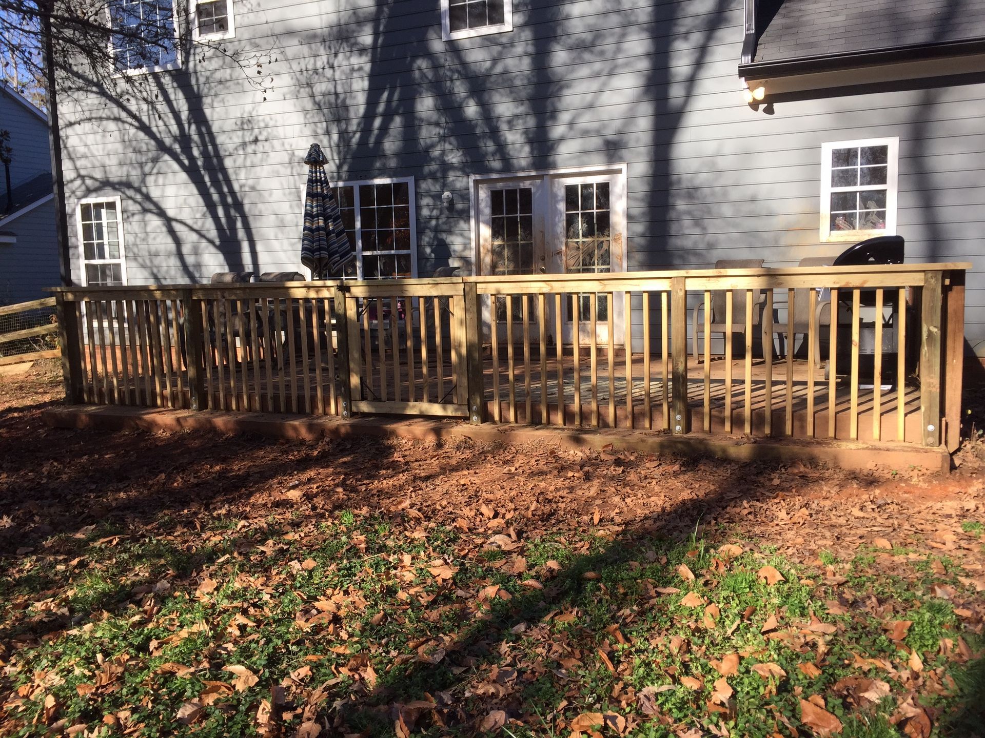 A wooden deck is in the backyard of a house.