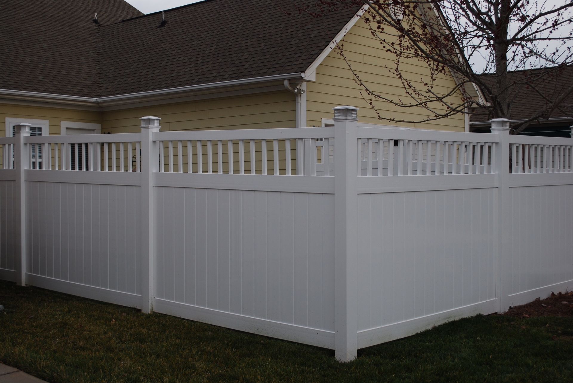 A white fence is in front of a house