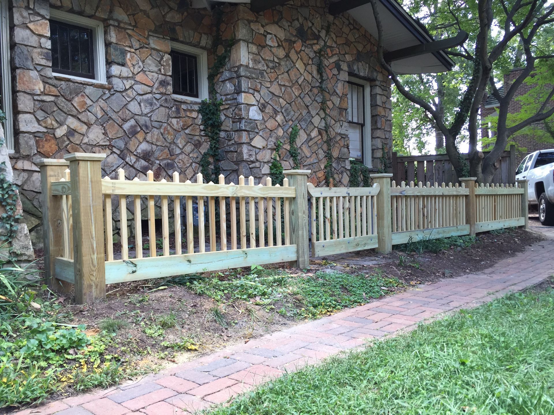 A wooden fence is in front of a stone house.
