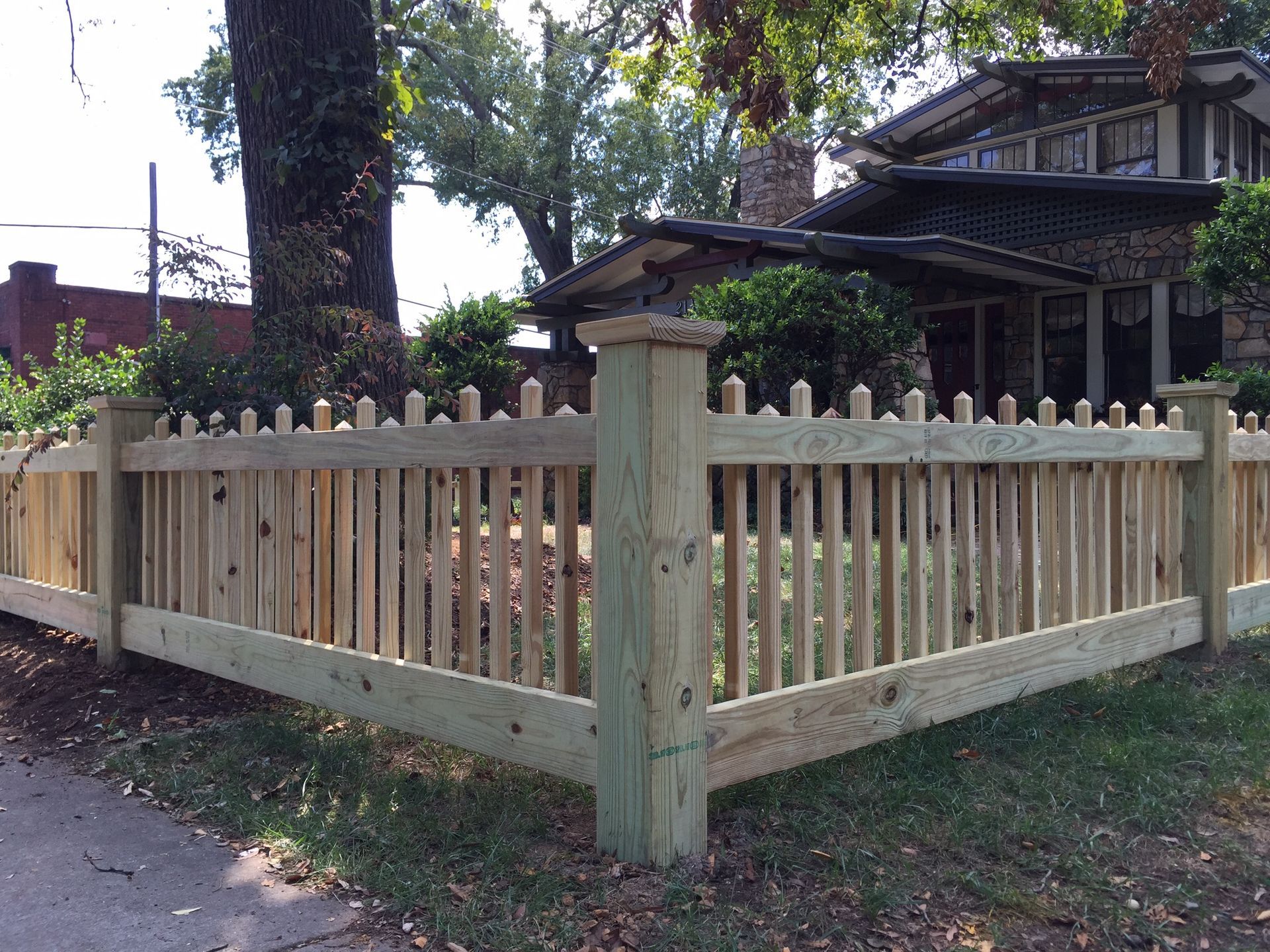 A wooden picket fence is in front of a house