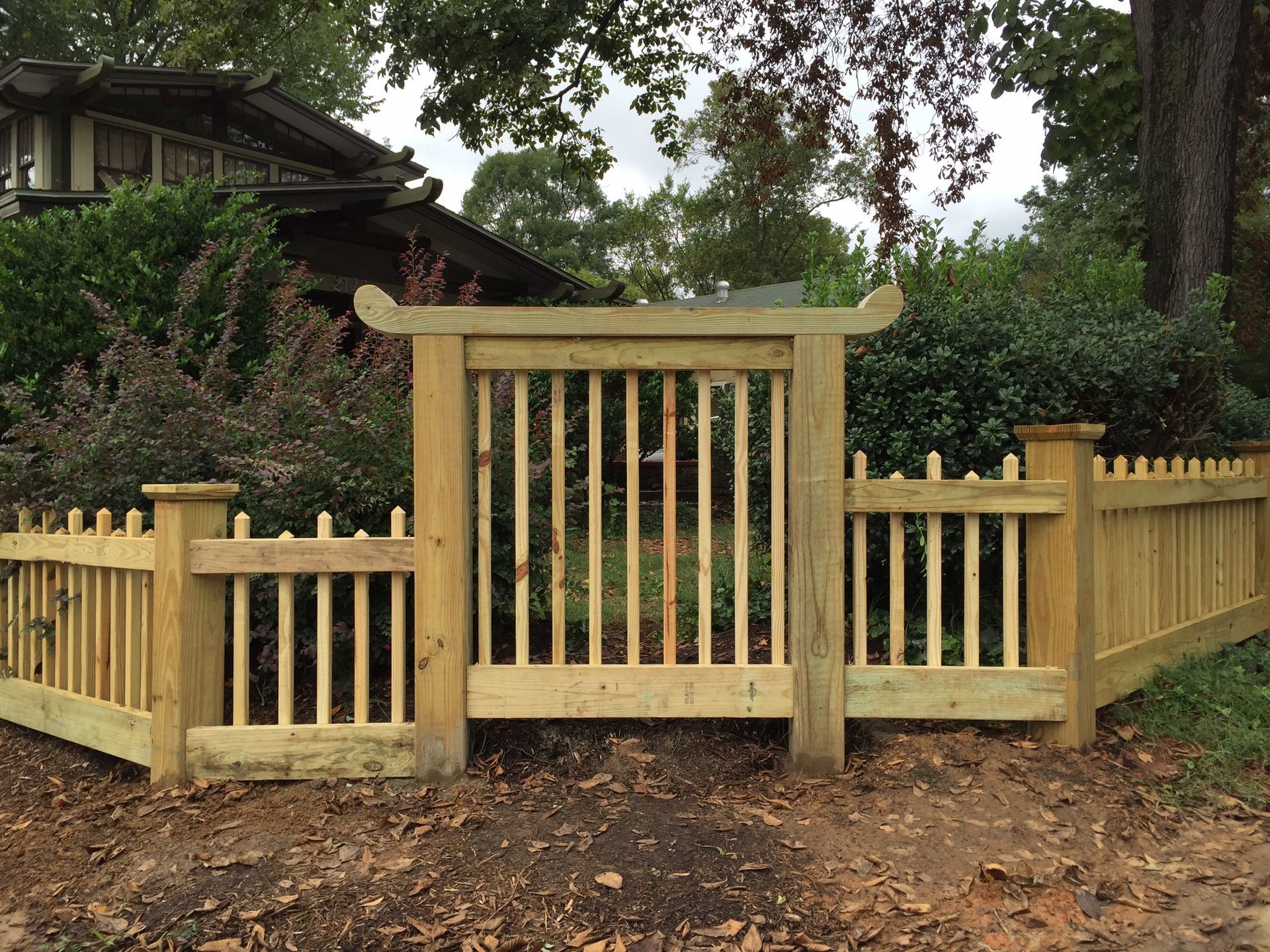 A wooden fence with a gate in front of a house