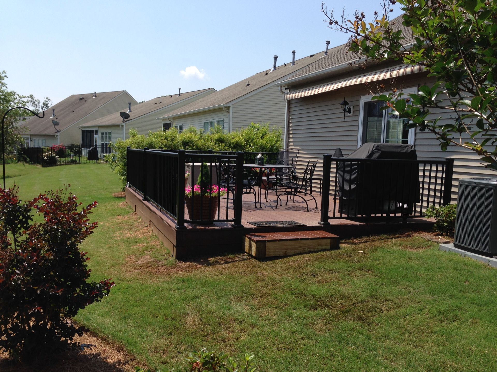 A backyard with a deck and a house in the background