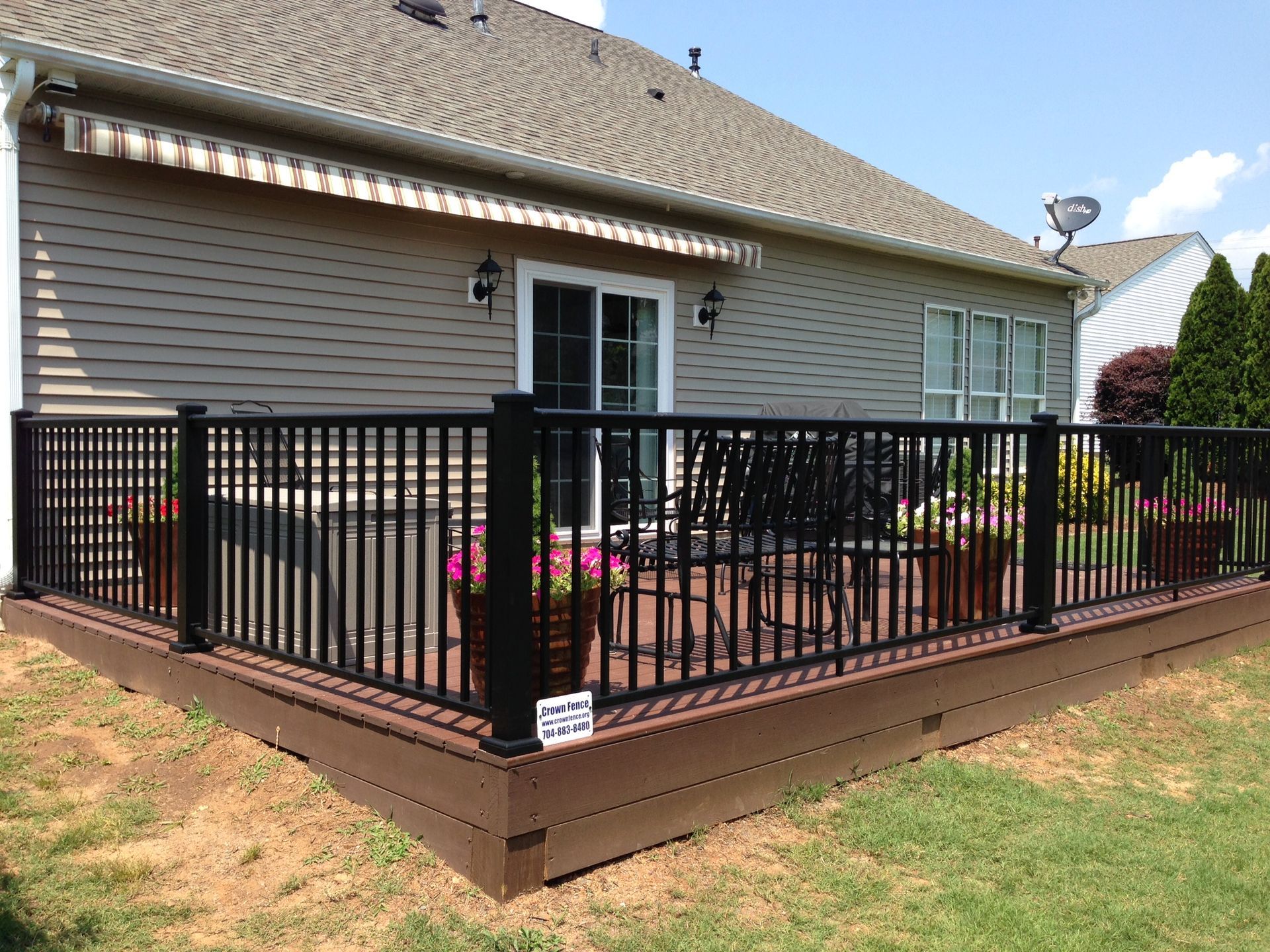 A deck with a black railing in front of a house