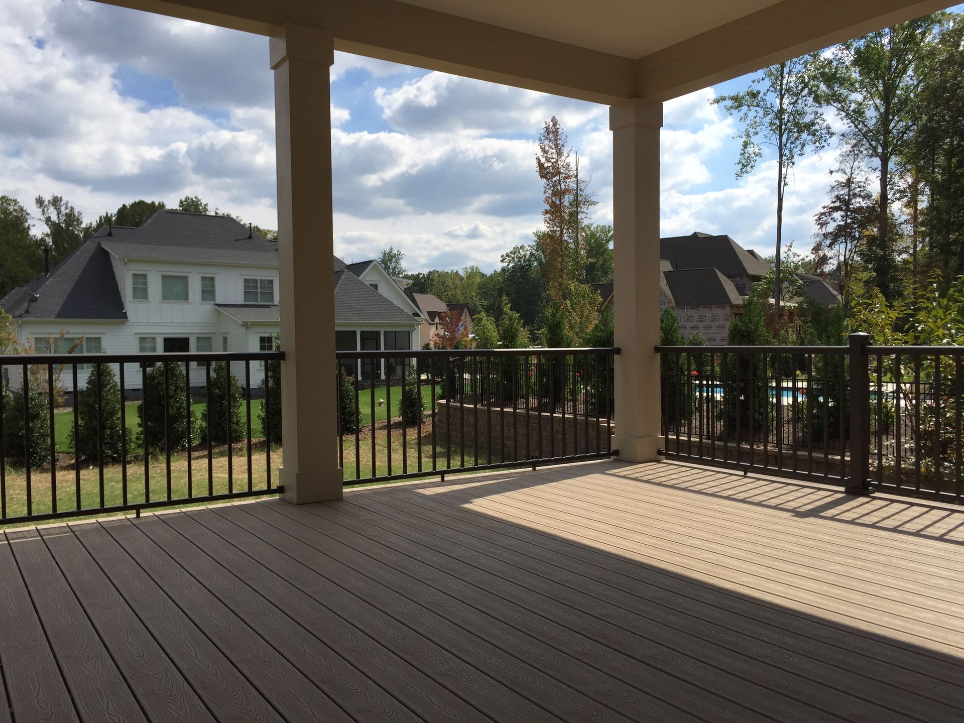 An empty deck with a railing and a house in the background