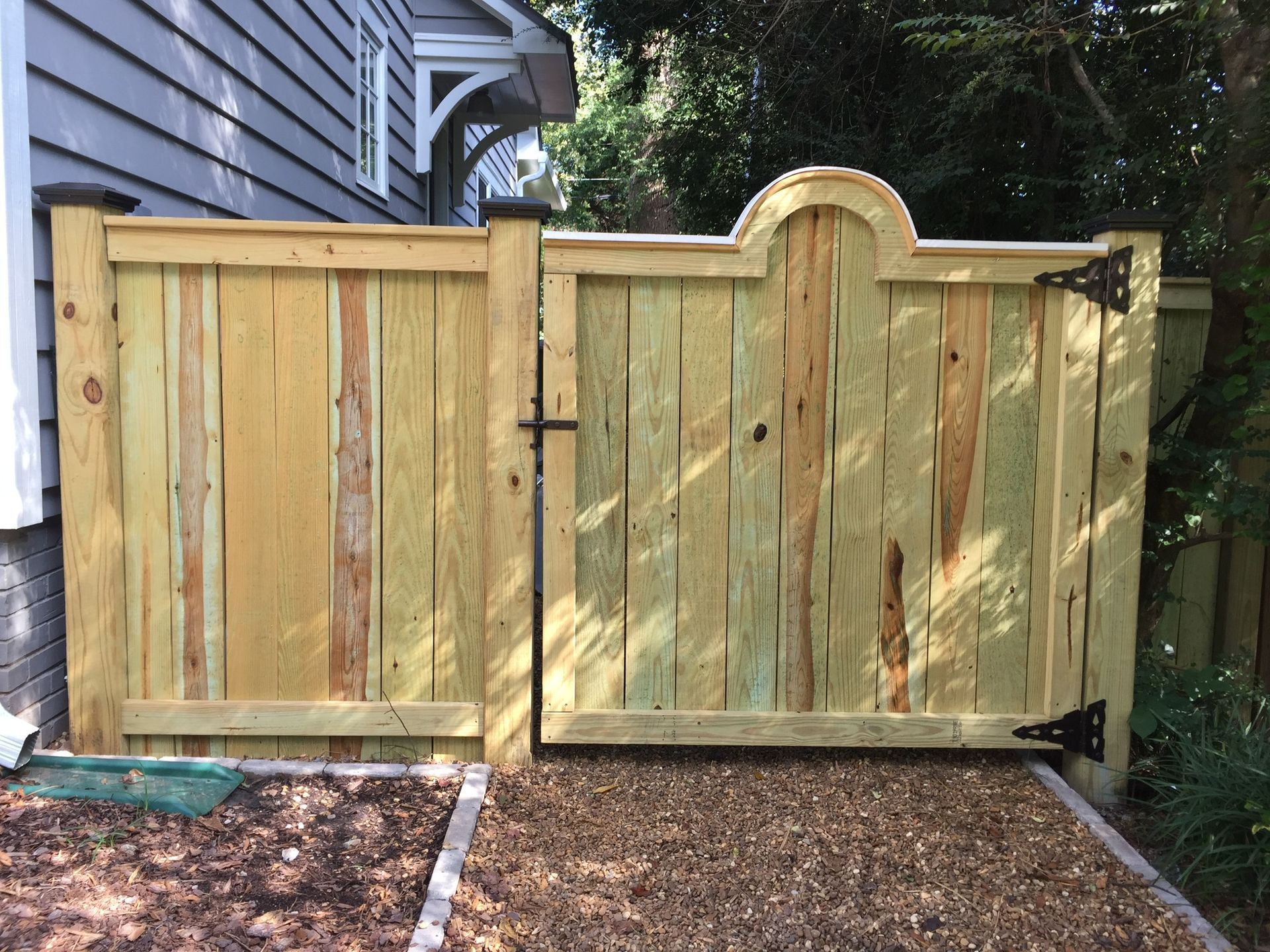 A wooden fence with a gate in front of a house.