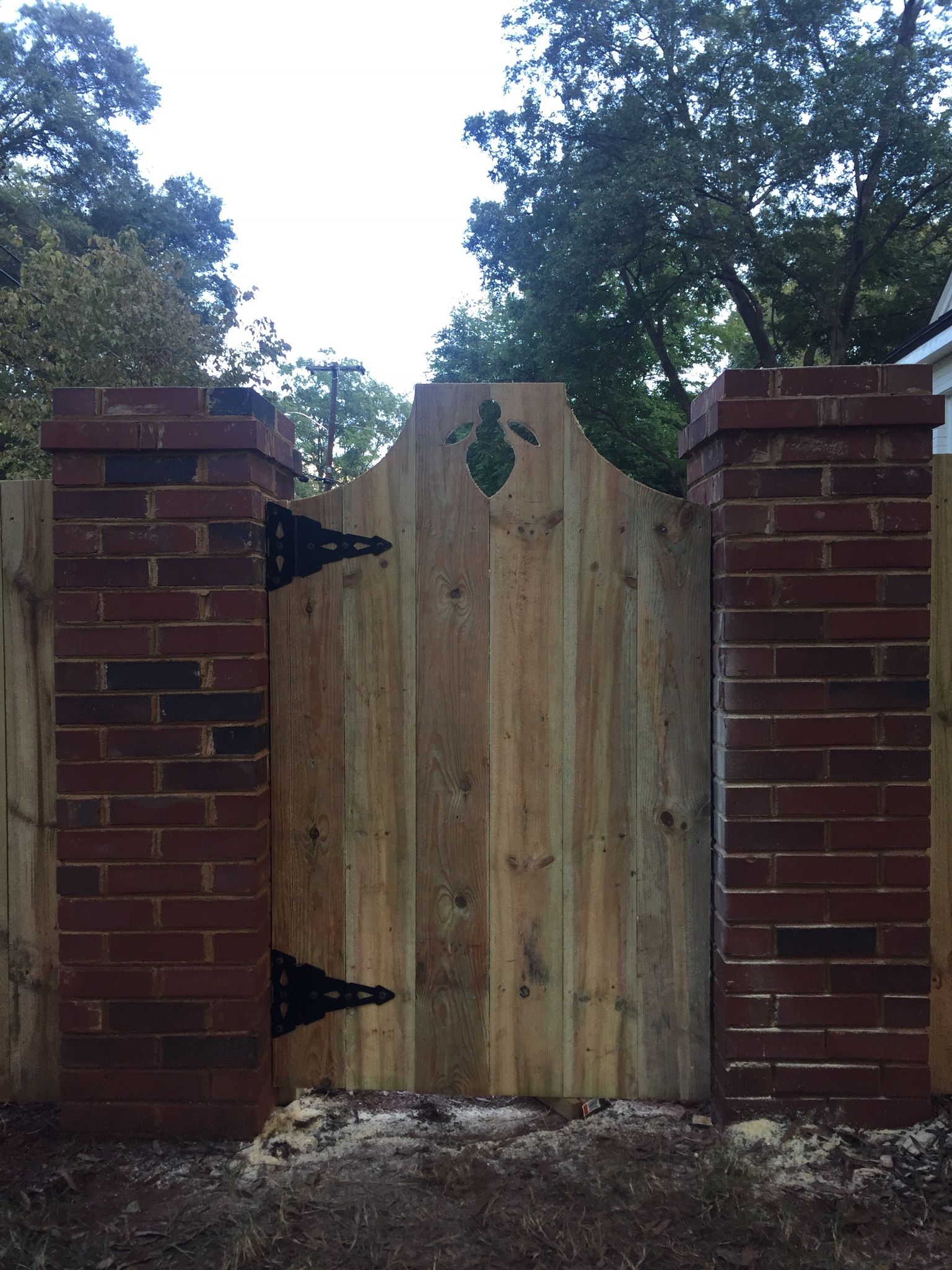 A wooden gate is between two brick pillars
