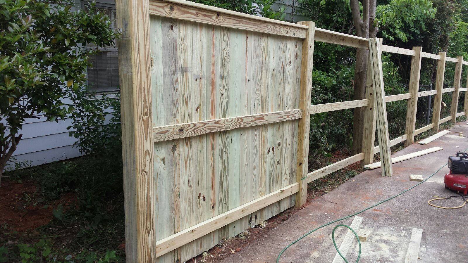 A wooden fence is being built in front of a house.