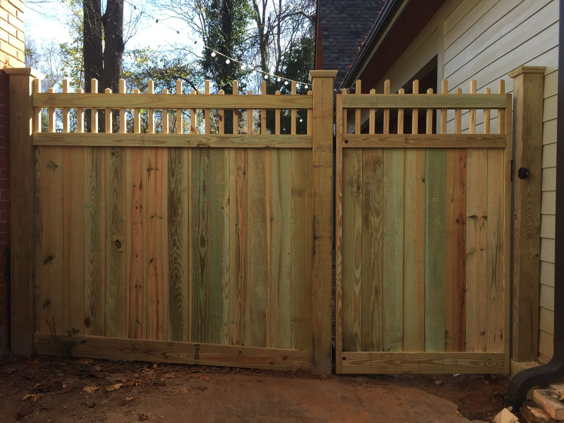 A wooden fence with a gate in front of a house