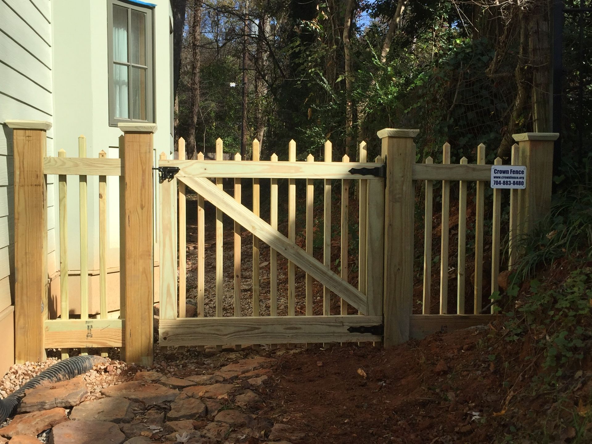 A wooden fence with a gate in front of a house