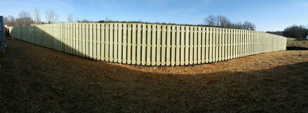 A white wooden fence is in the middle of a grassy field.