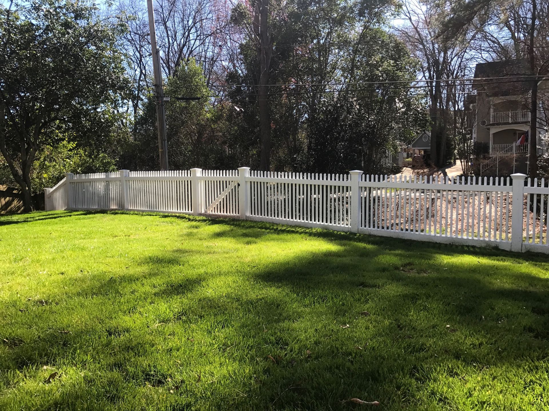 A white picket fence surrounds a lush green field.
