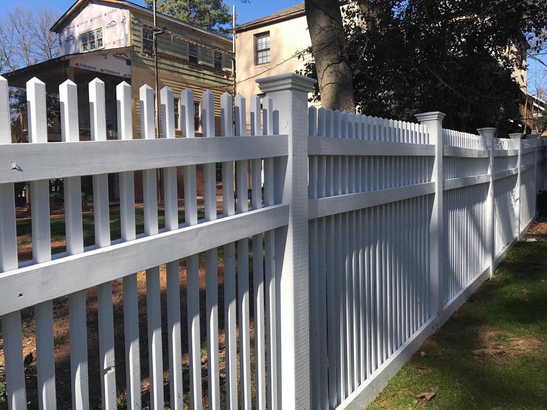 A white picket fence is in front of a house.