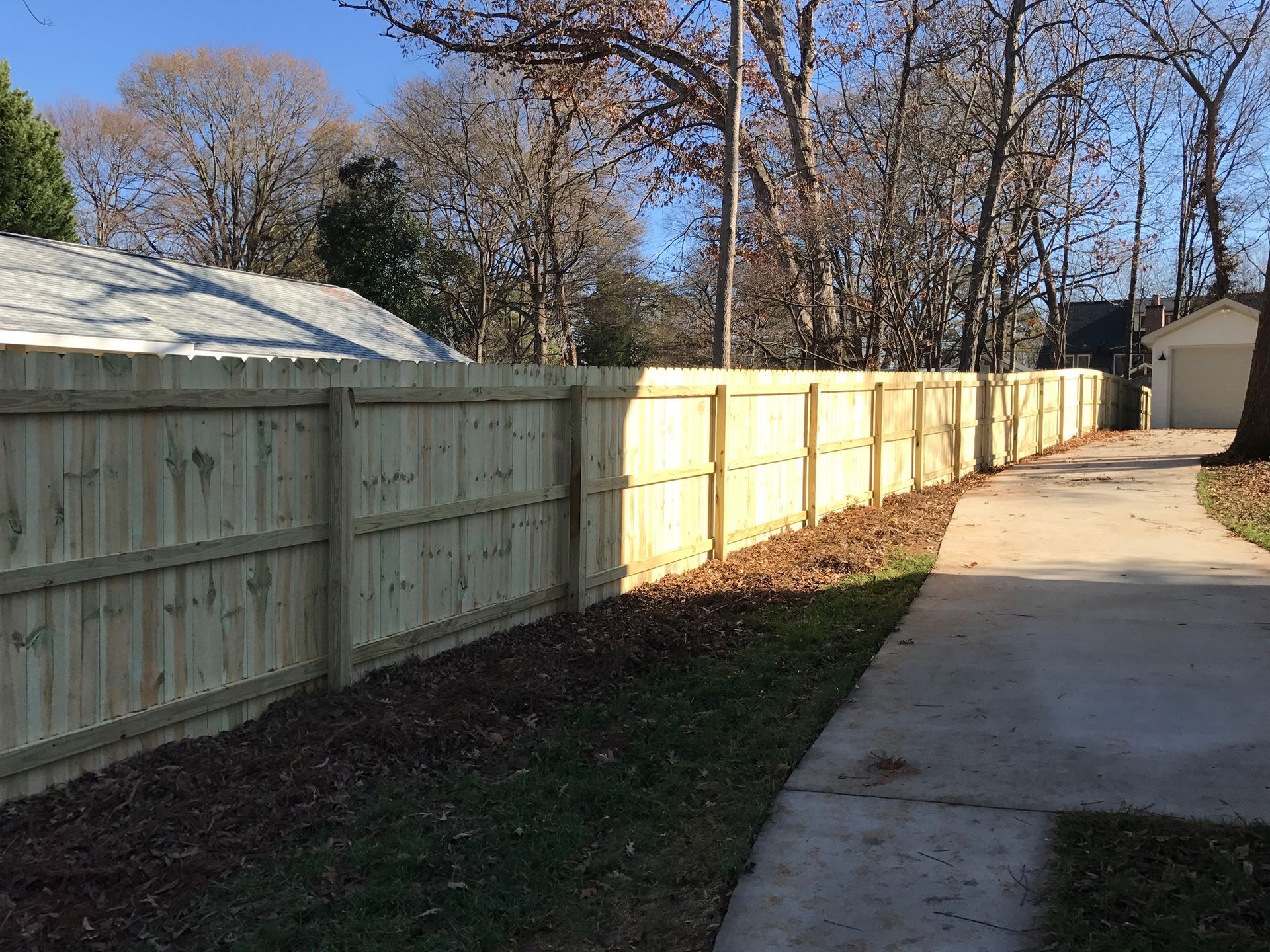 A wooden fence along a sidewalk next to a house.