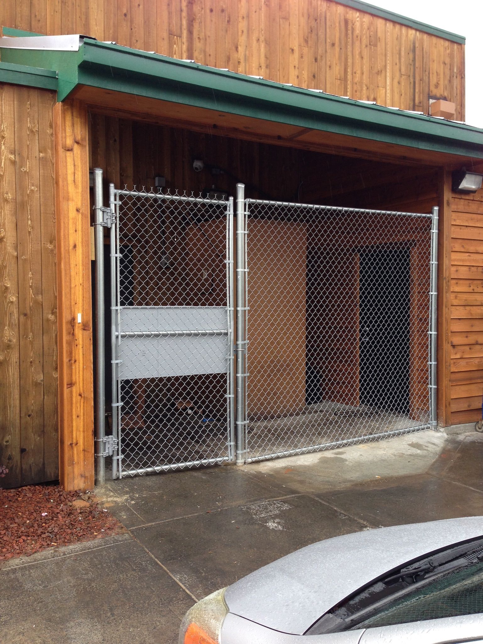 A car is parked in front of a building with a chain link fence