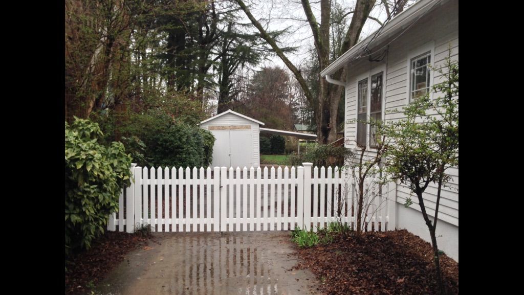 A white picket fence is in front of a white house.