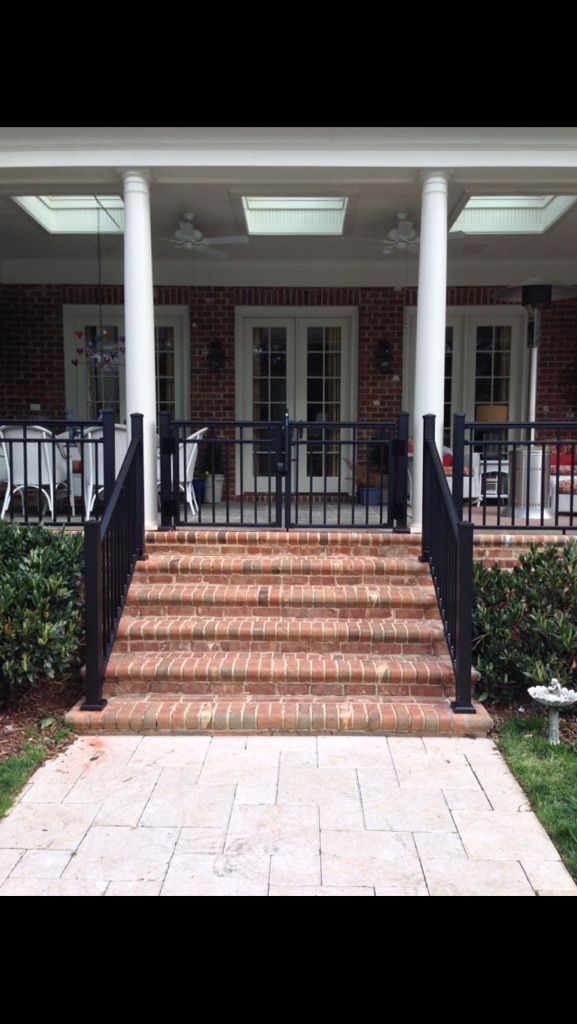 A brick house with a black railing and stairs