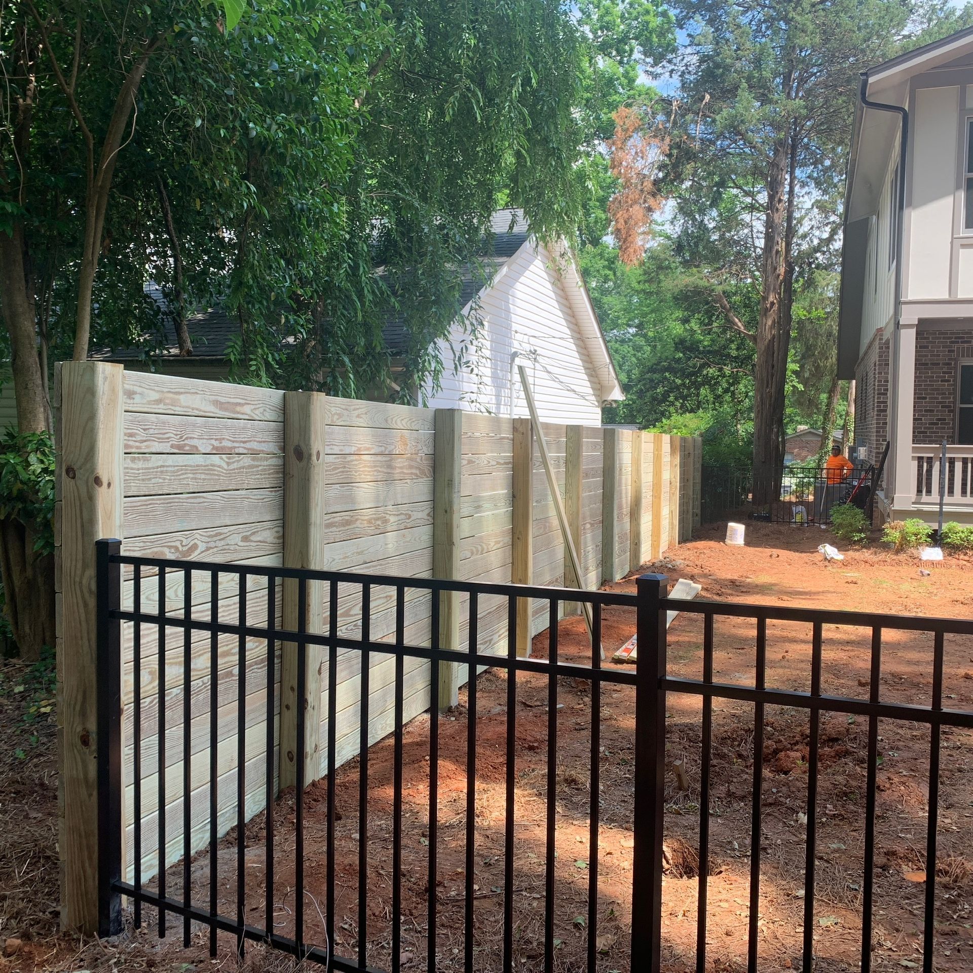 A black gate with a brick wall behind it