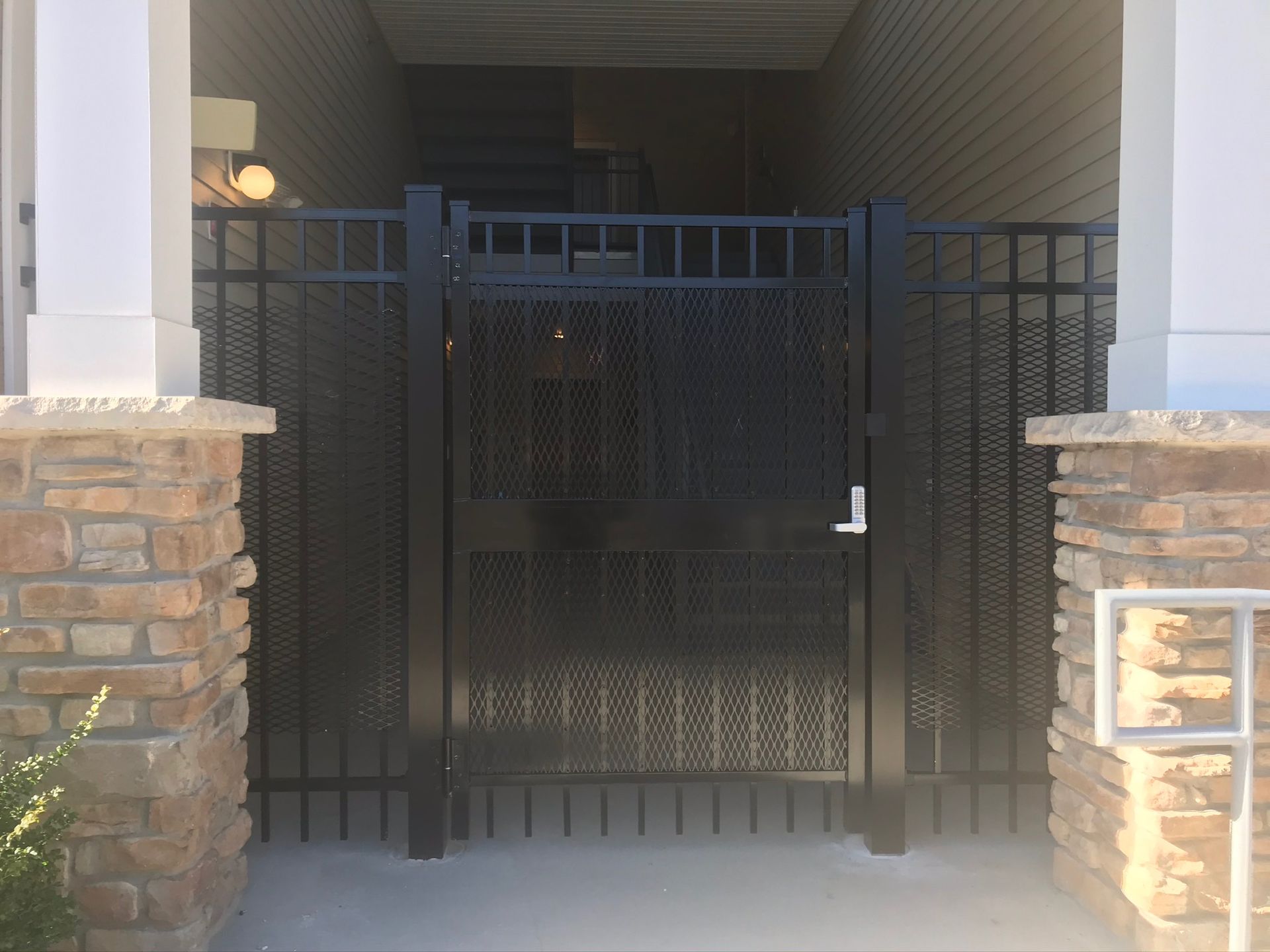A black gate with a brick wall behind it