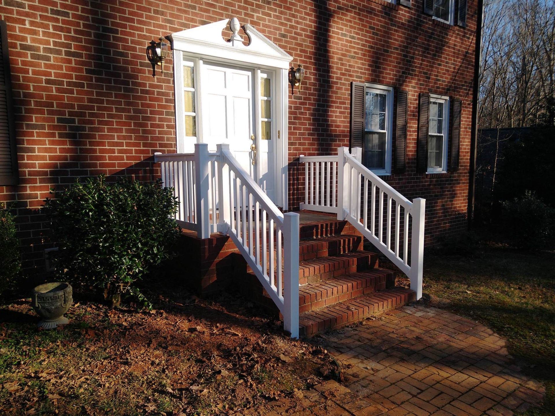 A brick house with a white railing and stairs