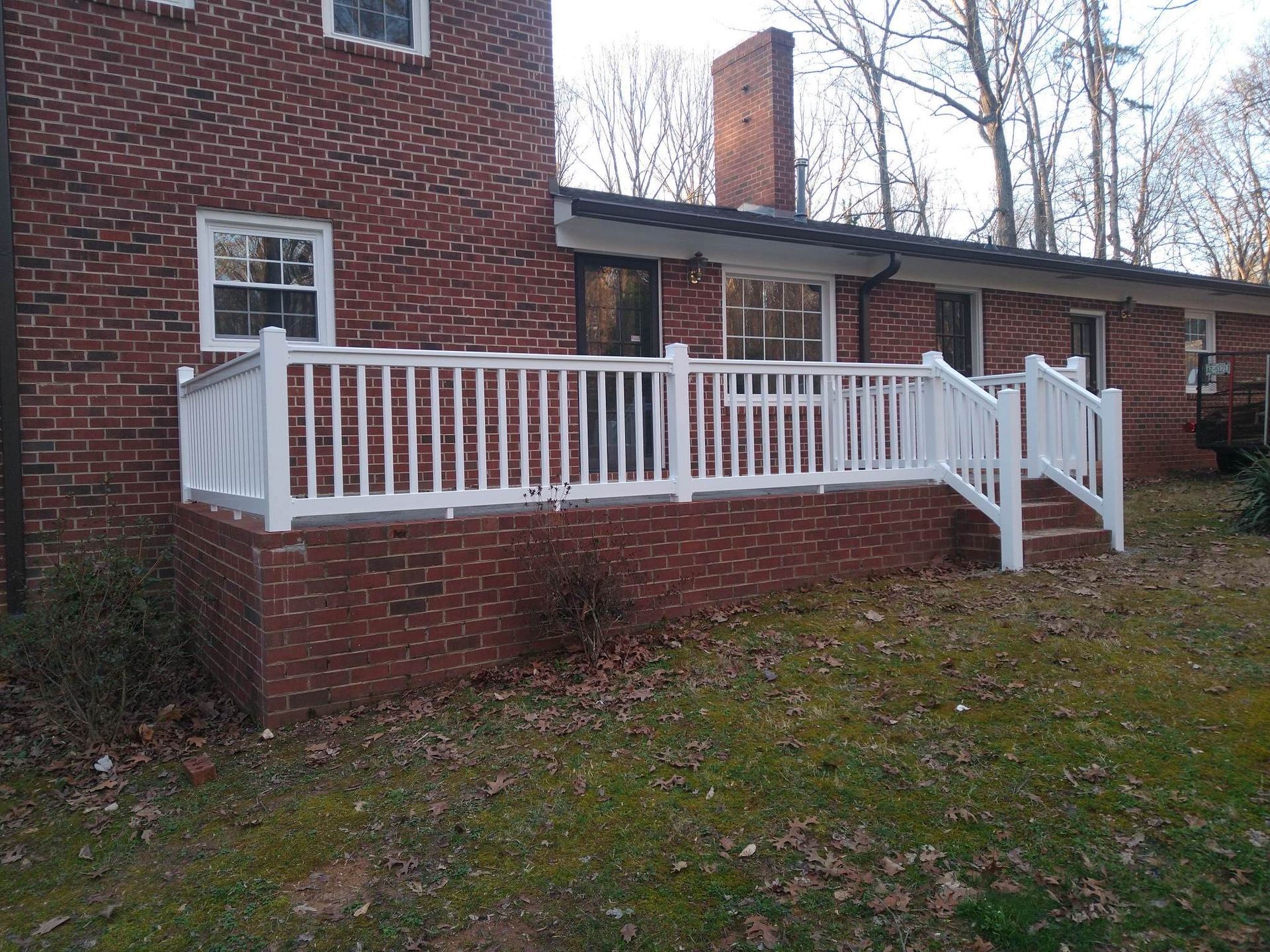 A brick house with a white deck in front of it.