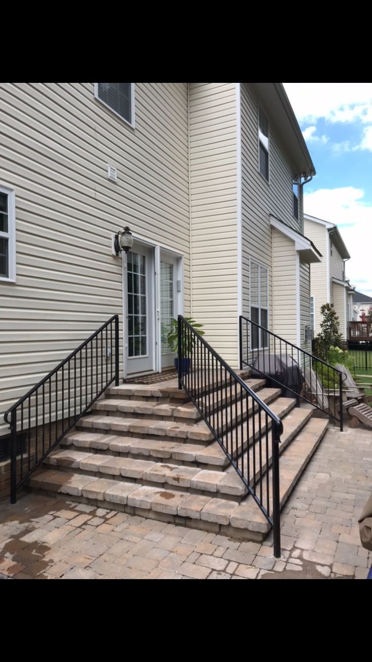 A house with stairs leading up to the front door and a wrought iron railing.
