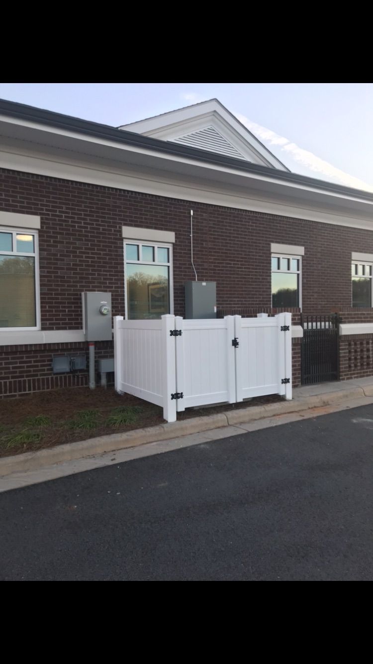 A white fence is in front of a brick building.