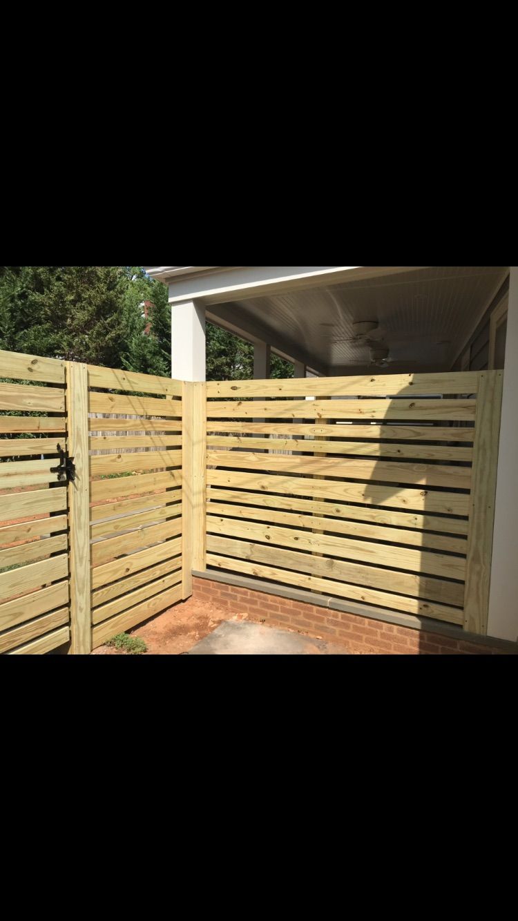 A wooden fence with a gate in front of a house.