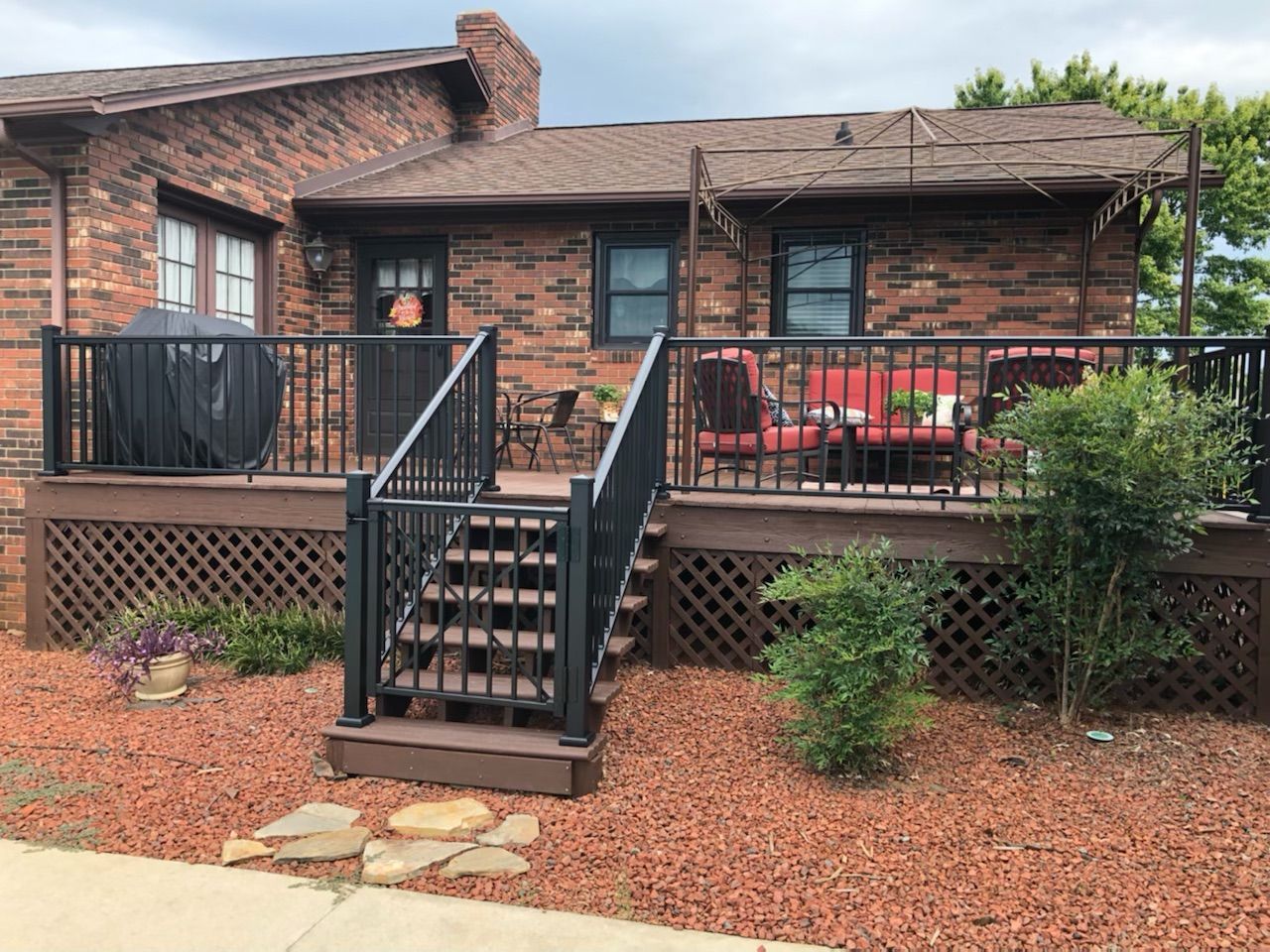 A brick house with a deck and stairs in front of it.