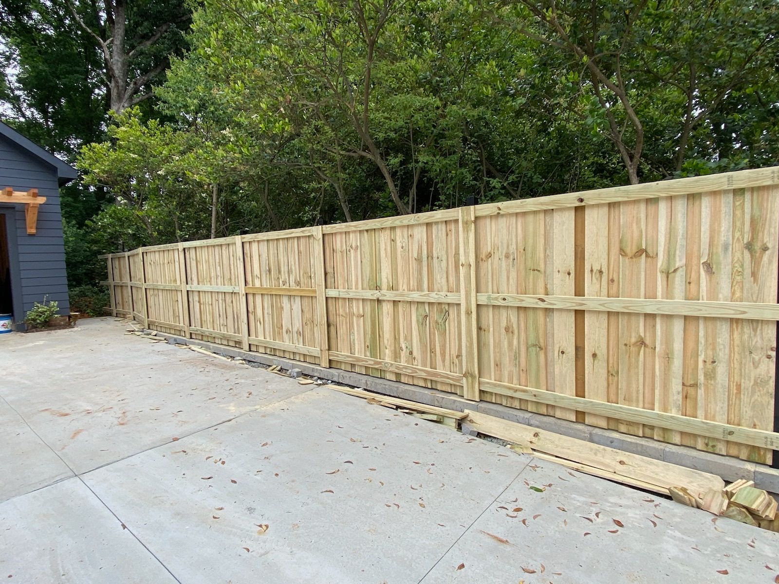 A wooden fence is sitting on top of a concrete driveway next to a house.
