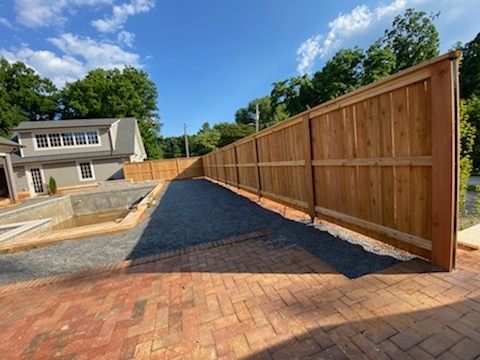 A wooden fence with a metal fence in front of a house.