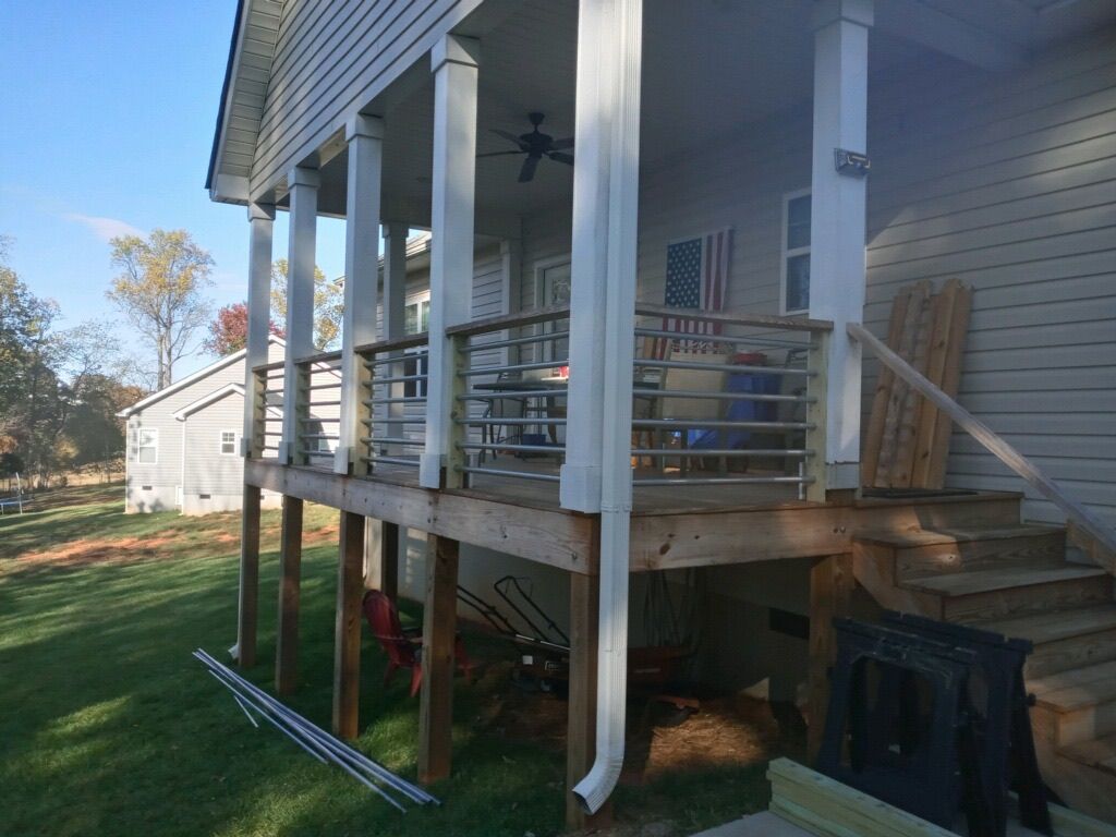A wooden deck with stairs and a ceiling fan on the side of a house.
