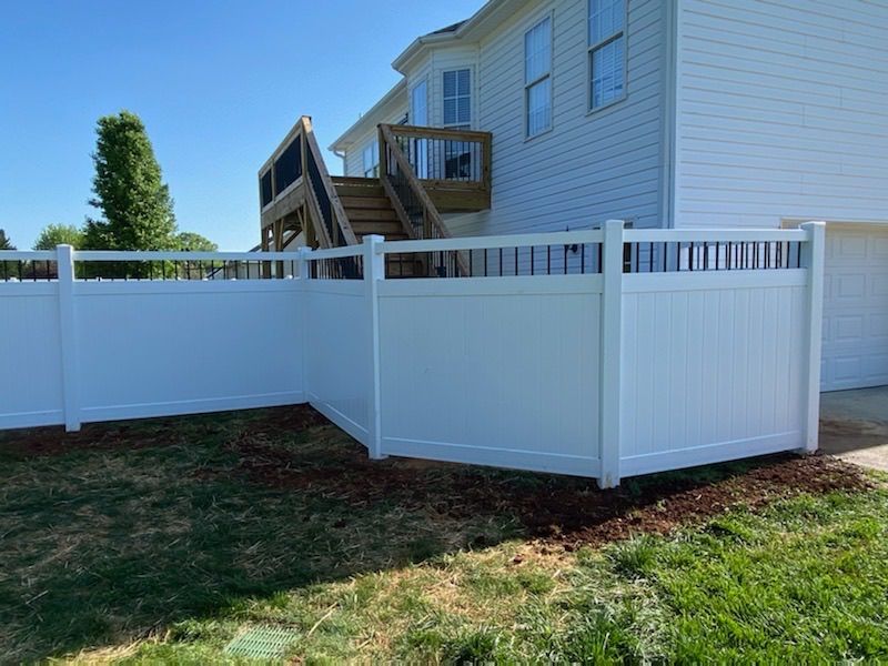 A white fence is in the backyard of a house.