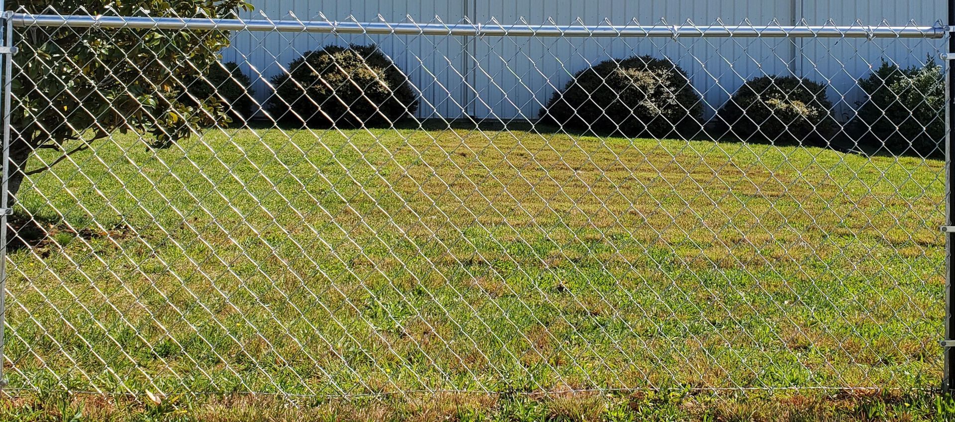 A chain link fence surrounds a lush green field.