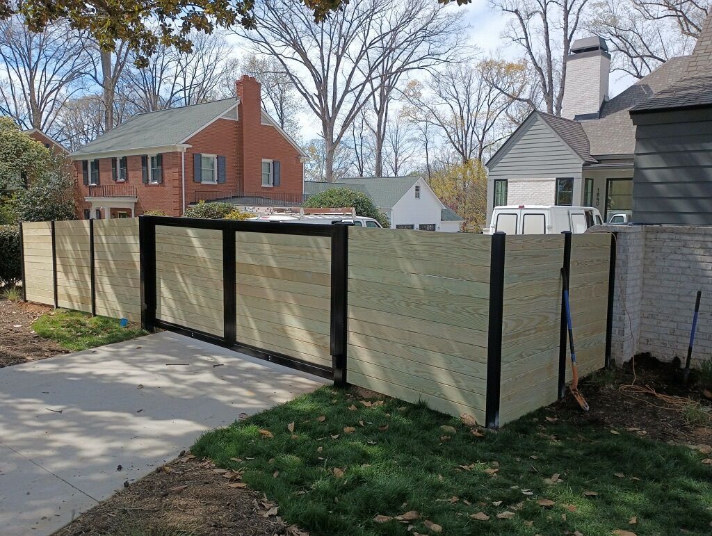 A wooden fence in front of a brick house
