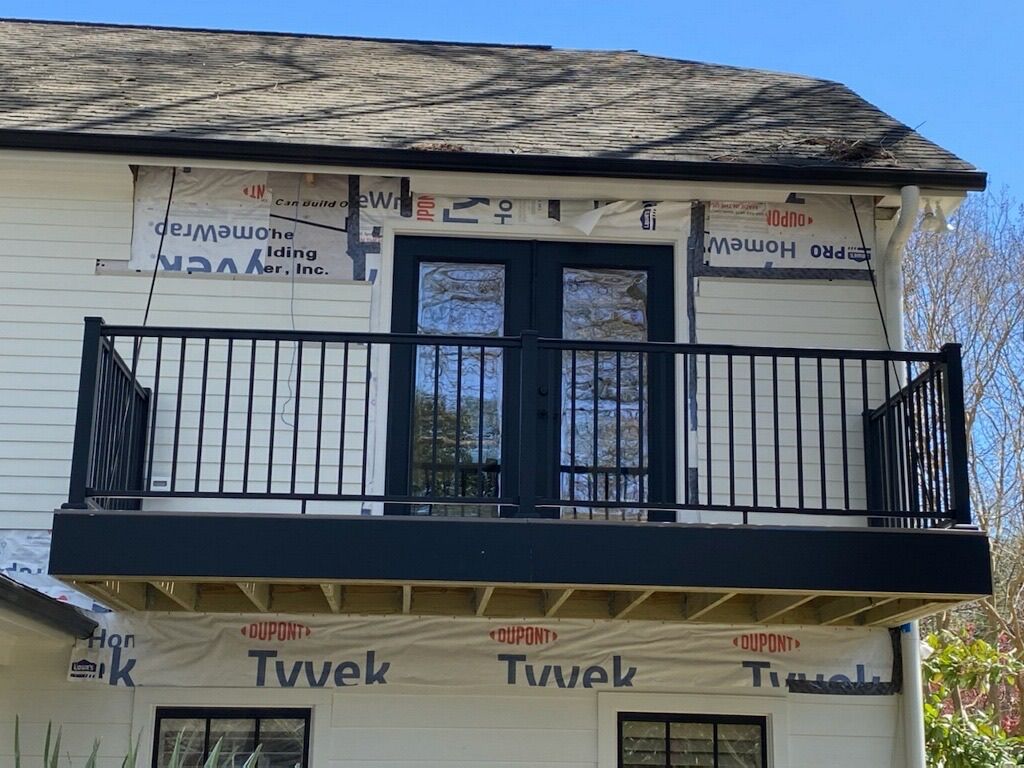 A white house with a balcony and a black railing