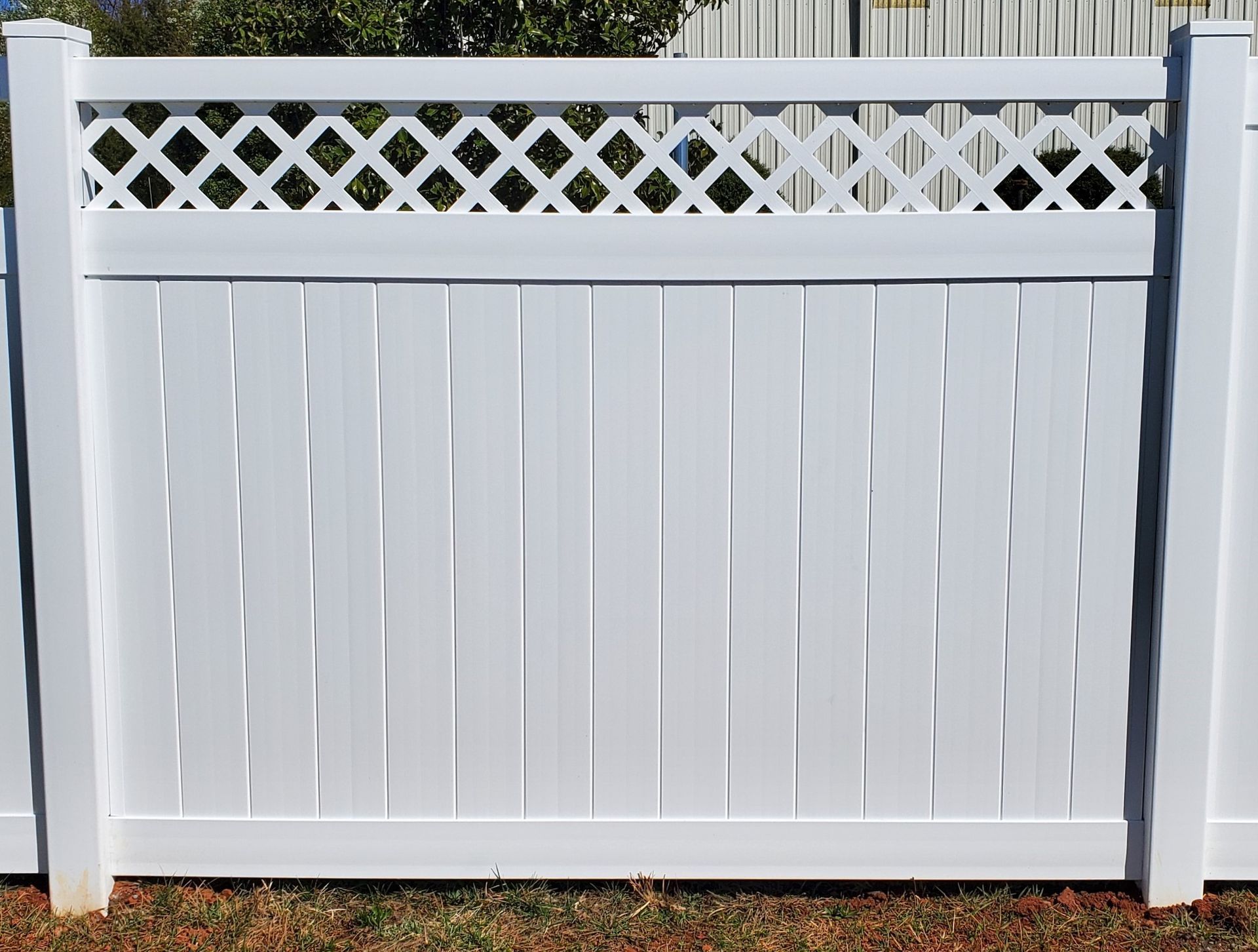 A white fence with a lattice on top of it