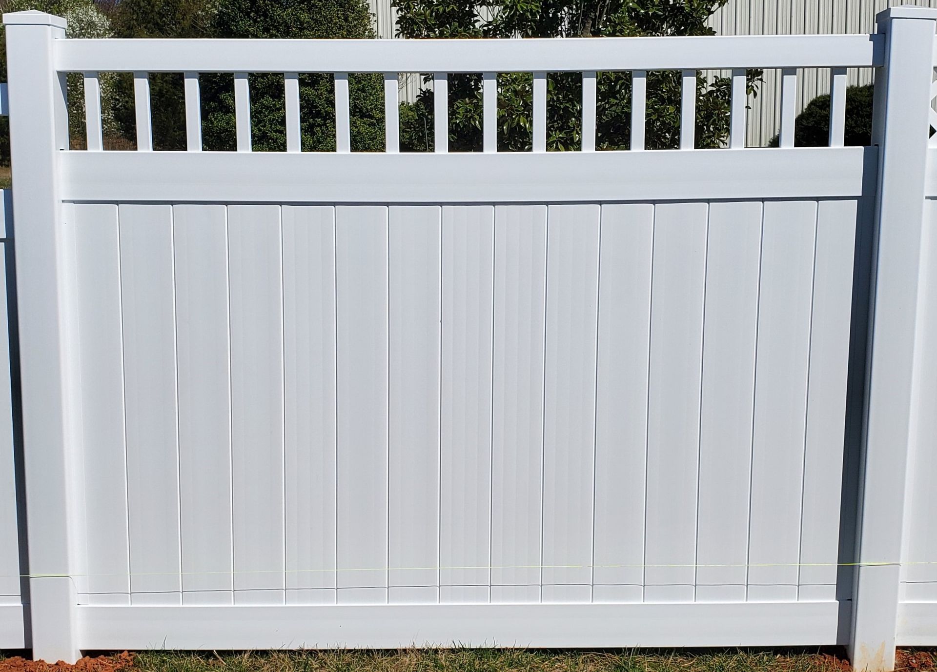 A white fence with a few trees in the background