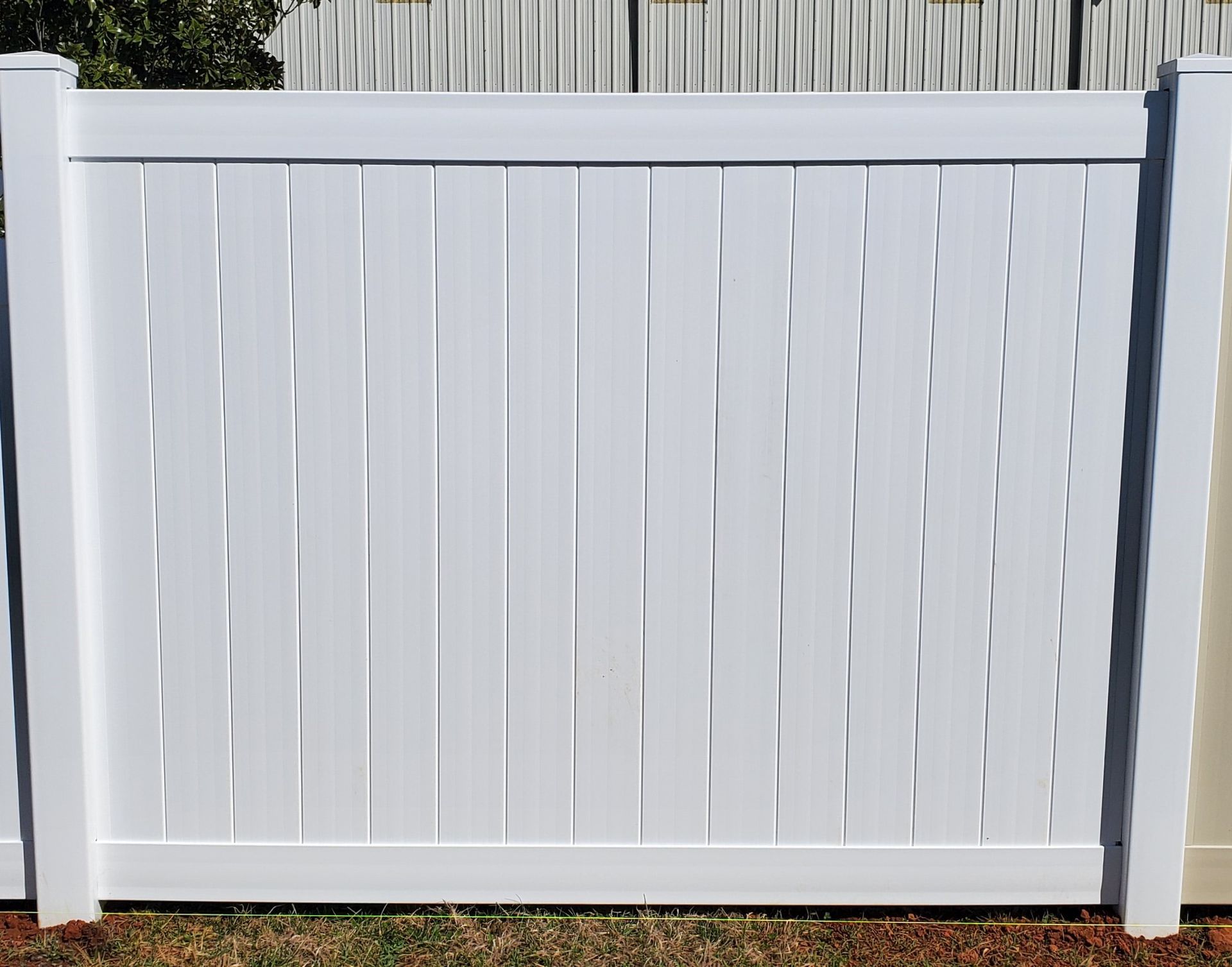 A white fence is sitting on top of a lush green field.