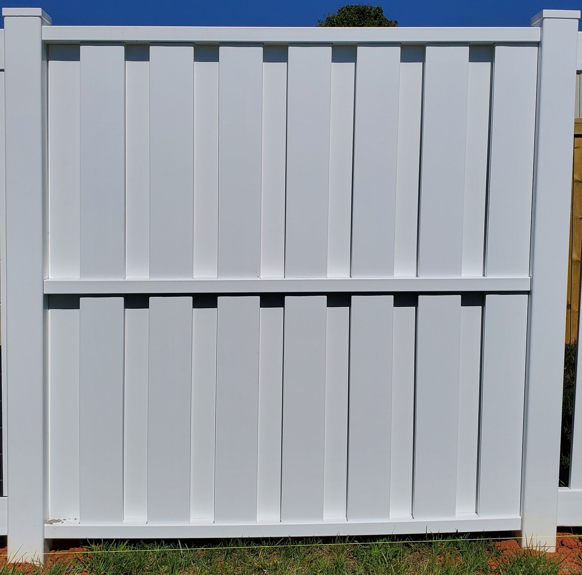 A white fence is sitting on top of a lush green field.