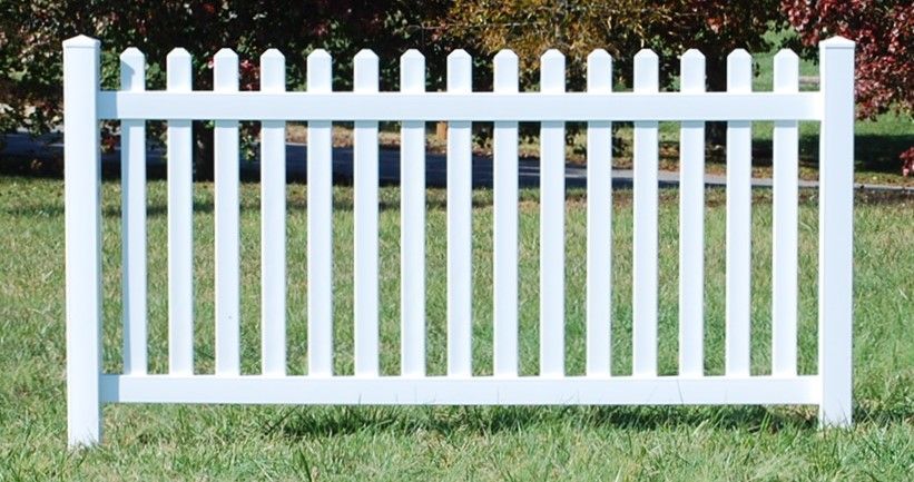 A white picket fence is sitting in the grass
