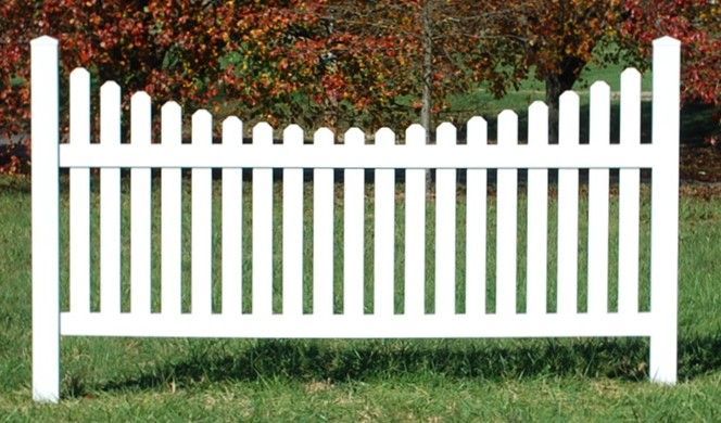 A white picket fence is sitting on top of a lush green field.