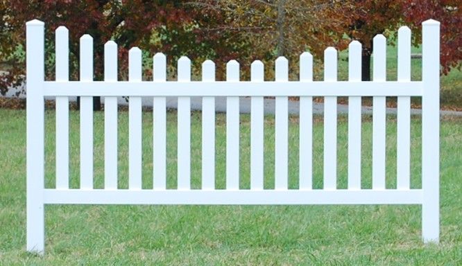 A white picket fence is sitting in the middle of a lush green field.