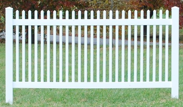 A white picket fence is sitting in the middle of a lush green field.